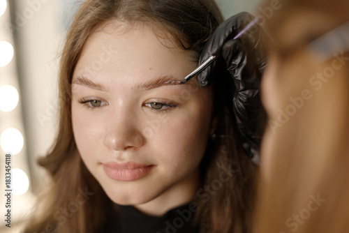 Young woman receiving eyebrow shaping treatment by skilled beauty artist in a bright salon