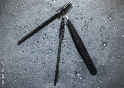 Obraz na płótnie Beauty tools for eyebrow shaping and eyelash enhancement on a textured wet surfa
