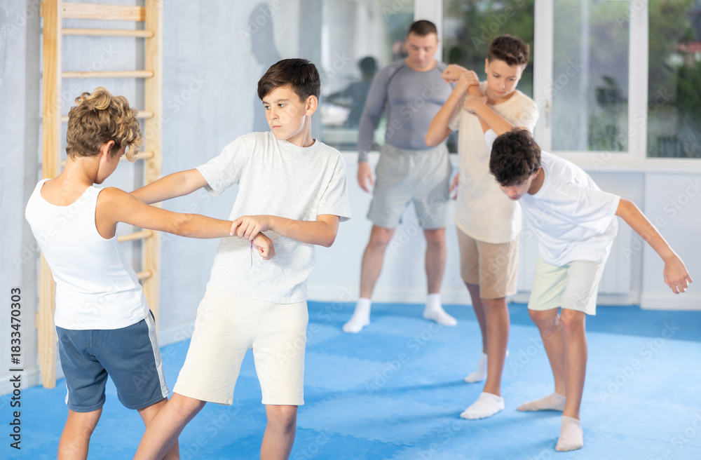 Naklejka premium Diligent preteen student practicing self-defense techniques in pairs during workout session