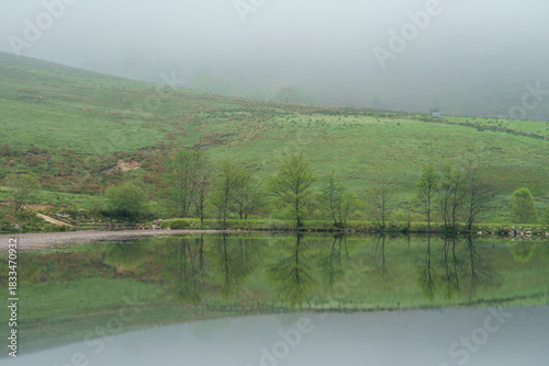 Misty Morning Reflection on a Calm Lake in a Green Valley