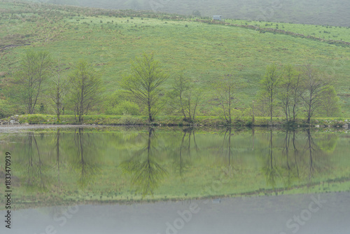 Misty Morning Reflection on a Calm Lake in a Green Valley