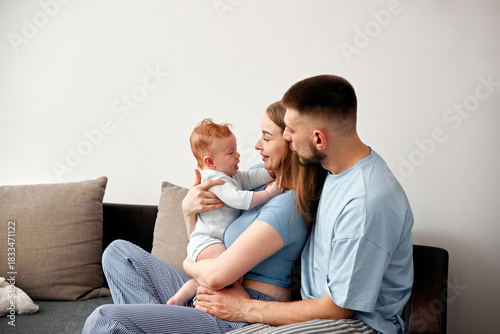 Family spending time together in a cozy living room with a baby on a sofa during the day
