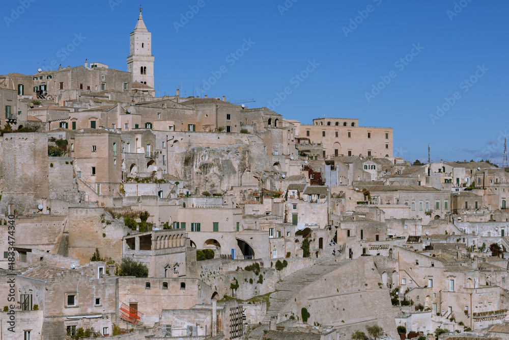 Obraz premium sassi di matera, italy: ancient, pale stone cave dwellings and historic city center under a deep blue sky. unesco world heritage site in basilicata