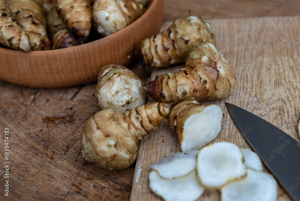 Fototapeta premium Fresh Sliced Jerusalem Artichokes on Wooden Cutting Board