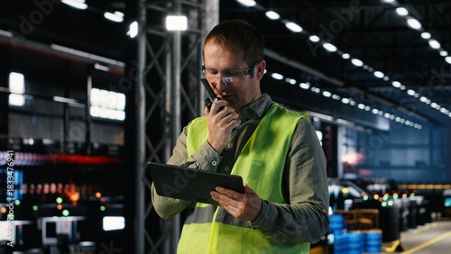Employee speaking through walkie talkie radio to oversee machinery operation, demonstrating manpower and the professional responsibility in manufacturing and production.