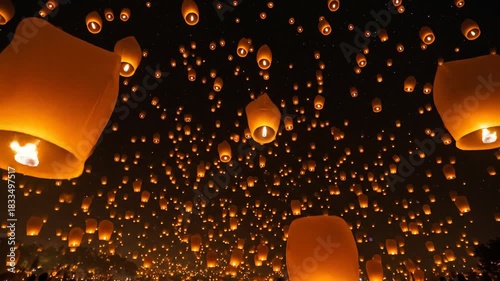 Thousands of glowing orange sky lanterns ascend into a dark starfilled night