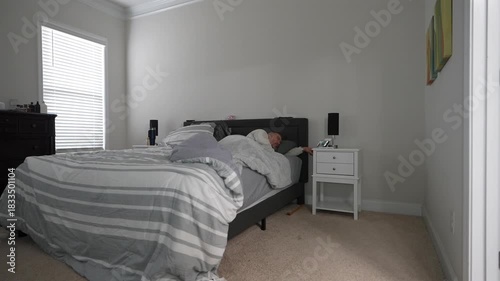man waking up and reaching for phone on nightstand