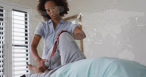 Foto Lifting mid caregiver wearing blue shirt holding senior patient's leg in bedroom