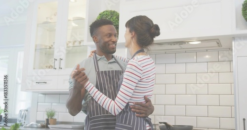 Cooking couple wearing striped aprons making dinner in home kitchen, frying pan on stove