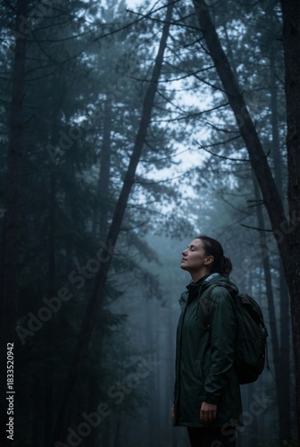 Peaceful female hiker breathing deeply in dense foggy pine forest solitude