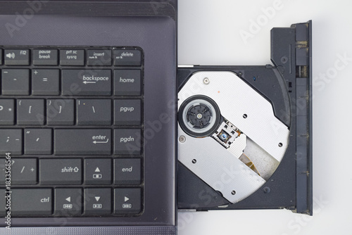 Top view of laptop keyboard with open CD drive showing optical disc mechanism, minimal tech photo suitable for repair, hardware, or data transfer concept.