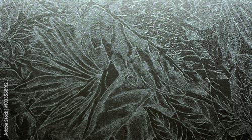 A close-up of a plant leaf engraving on a polished black marble surface.