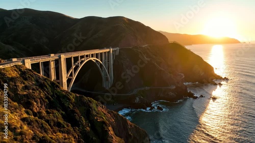 Iconic concrete arch bridge hugging a rugged coastline as the sun sets over the vast pacific ocean 4k video