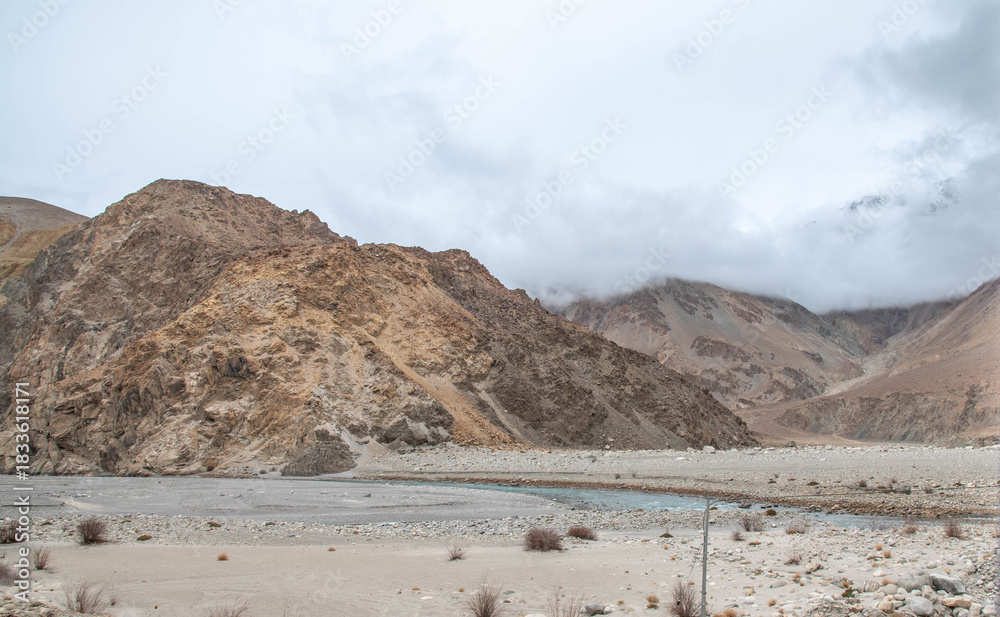 Fototapeta premium Beautiful mountain landscape in Nubra, Ladakh featuring a dry riverbed running through the center. Rugged Himalayan terrain with serene valleys, textured earth patterns, and stunning natural beauty