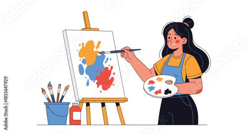Talented female artist in an apron painting a colorful abstract picture on a canvas with a brush and a palette in her hands.