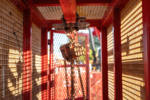 Metal pulley and hoist chain box, manual equipment using the lifting heavy object, it install on the beam of mobile toolbox. Industrial equipment object, close-up.