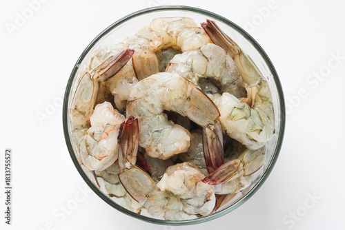 Photography Top view of fresh, raw shrimp, peeled and deveined with tails intact in a clear glass bowl