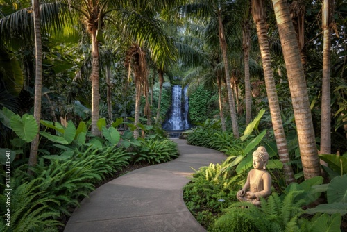 Tranquil jungle path leading to a serene waterfall with a buddha statue