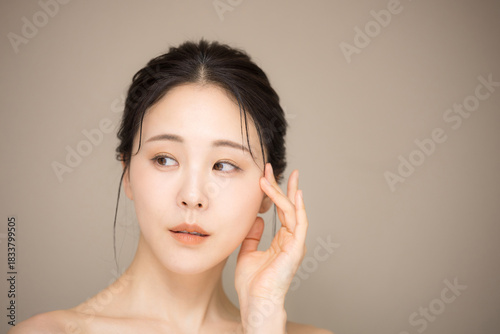 Fotografía 髪の毛がアップ背景がベージュの使いやすい美容やスキンケアの美しい女性のイメージ　クローズアップ