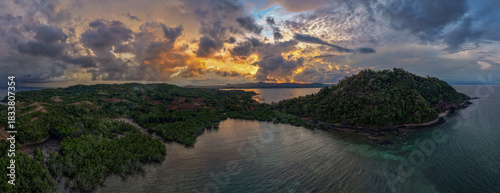 Panoramic sunrise aerial of Sakatia Island, Nosy Be, Madagascar – golden light over the ocean, tropical coastline, and peaceful island landscape.