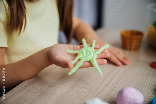 Bild auf Leinwand A little girl makes figurines out of colored airy plasticine, modeling dough