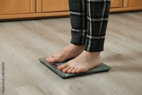 Tableau sur toile Man weighing himself on modern weighing scales at home, close-up of bare feet