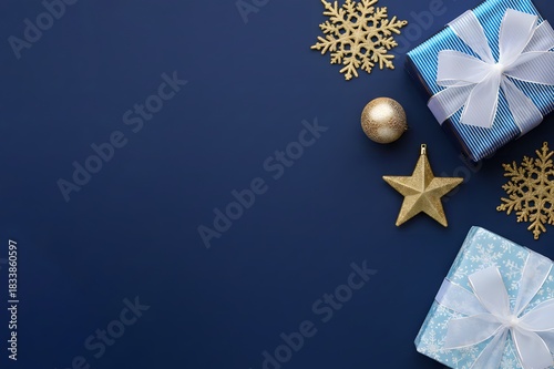 A flat lay of Merry Christmas and Happy Holidays greeting card, frame and banner. New Year. Noel. k gold Christmas ornaments and gifts, presents on blue background top view. Winter xmas holiday theme.