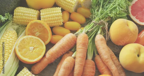 Fototapeta samoprzylepna Showing fresh produce on wood table, featuring carrots, corn, halved citrus, avocado, greens