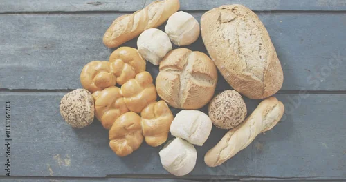 Fototapeta samoprzylepna Showing breads resting on weathered blue-gray plank, featuring crusty loaf, baguettes, seeded rolls