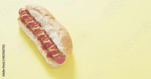 Fototapeta Sitting hot dog in soft bun on studio tabletop with mustard and ketchup drizzle, copy space