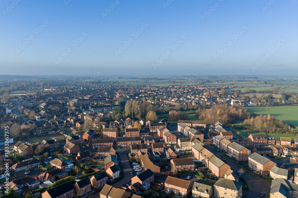 Fototapeta premium Aerial drone photo of the town of Batley in Wakefield in the UK, showing a typical British housing estate with rows of houses and homes near a public playing field on a sunny day in the winter time