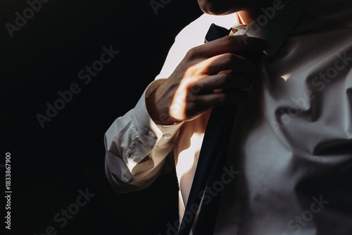 Fotografía Man adjusting tie by hand in dramatic light