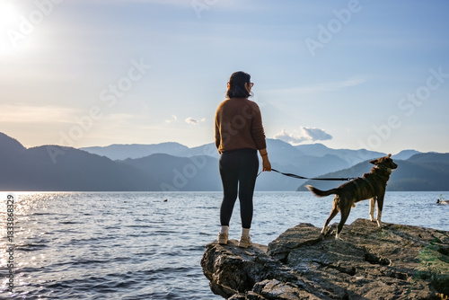 Woman and dog enjoying peaceful lake view and mountains at sunset