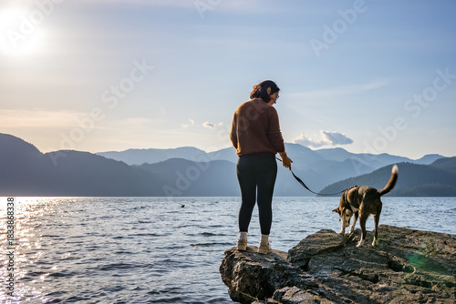 Woman and dog enjoying peaceful lake view and mountains at sunset