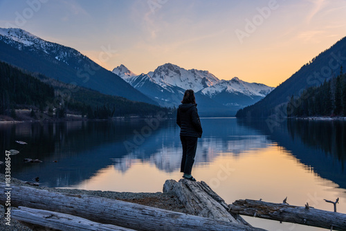 Woman standing on shoreline watching sunset over Duffey Lake