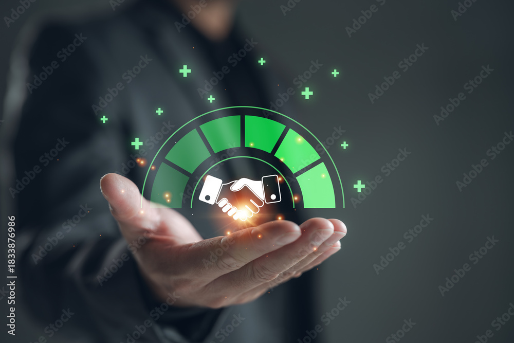 Fototapeta premium Businessman holding a digital partnership trust level meter with handshake icon. Concept of business collaboration, successful partnership, corporate trust, joint ventures, and mergers.