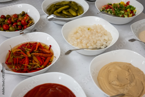 Wallpaper Mural Various pickled vegetables, sauces, and dips served in white bowls on a buffet table, prepared for a party or catering event. Torontodigital.ca