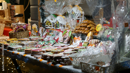 A bustling Christmas holiday market stall. Colorful array of cookies, gingerbread, and pastries wrapped as gifts. Festive decorations, and fragrant spices create a cozy family-friendly scene.