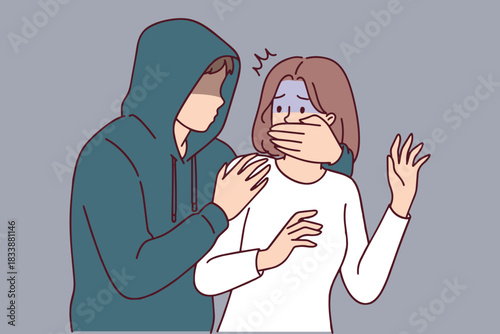 Hooded male figure grabs frightened female victim and shuts her mouth from behind. Concept of kidnapping, violence against women and criminal danger.