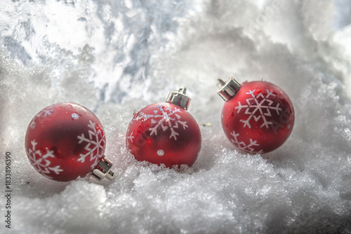 closeup on three red Christmas baubles with snowflake shaped on the snow for winter composition.