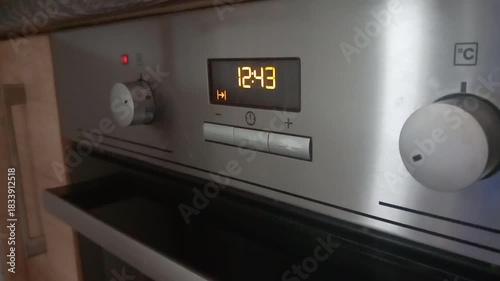 Digital control panel shows time while oven alarm beeps and cooling fan runs in kitchen setting