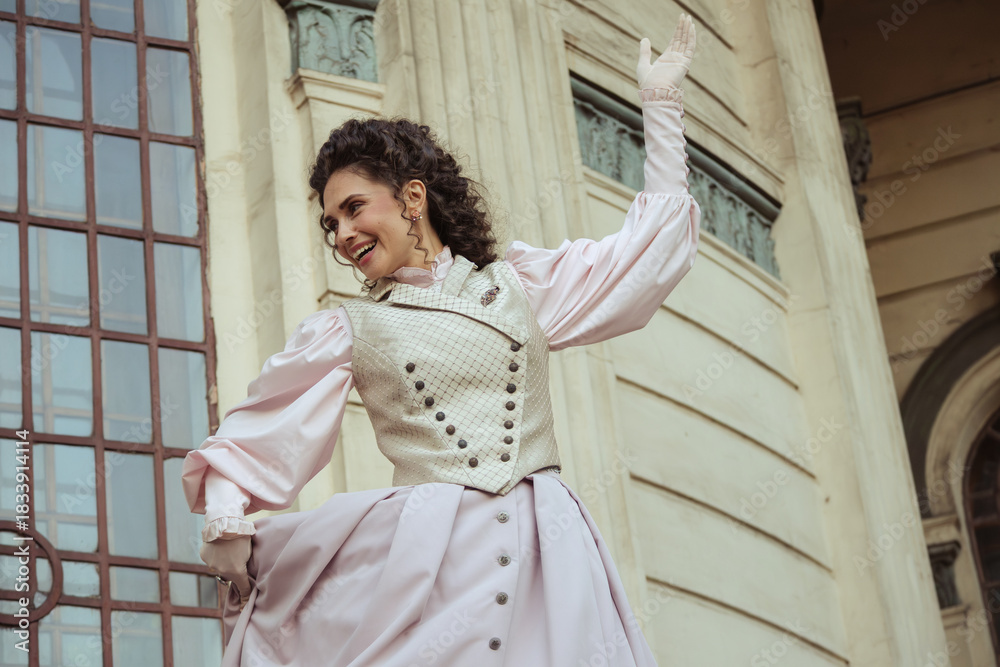 Fototapeta premium An elegant woman in a vintage dress stands by an old stone column