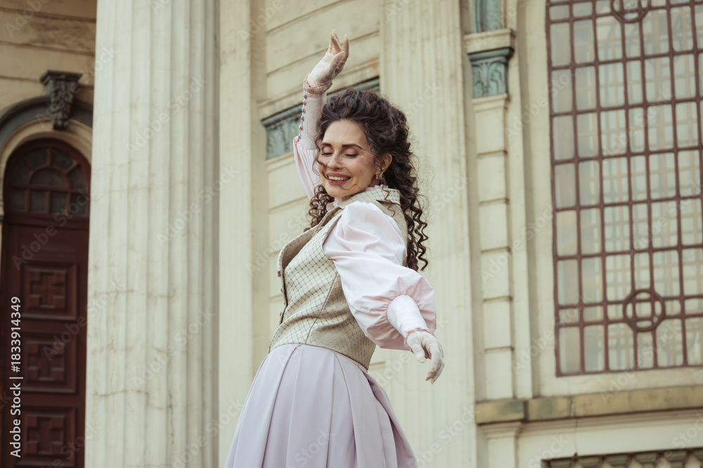 Fototapeta premium An elegant woman in a vintage dress stands by an old stone column