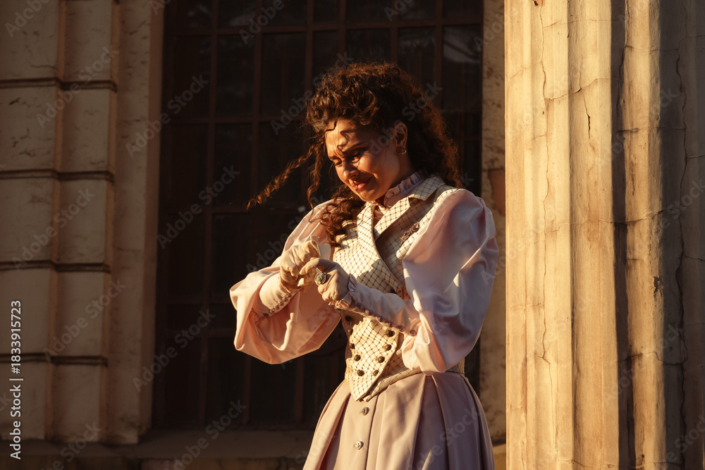 Fototapeta premium A woman in a vintage dress reads a letter near the columns of an ancient cathedral.