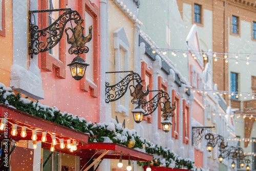 Cozy winter street view with building facades, snow, and illuminated lanterns