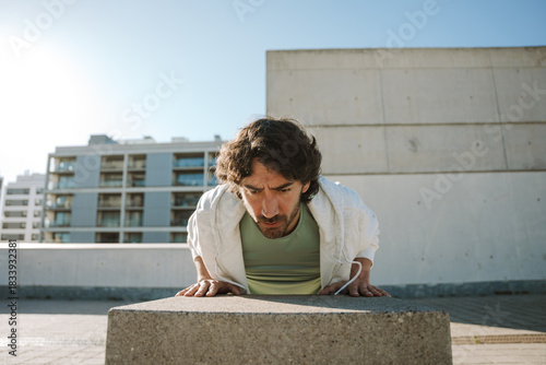 Konstfotografi A man leans his hands on a stone chair and does push-ups