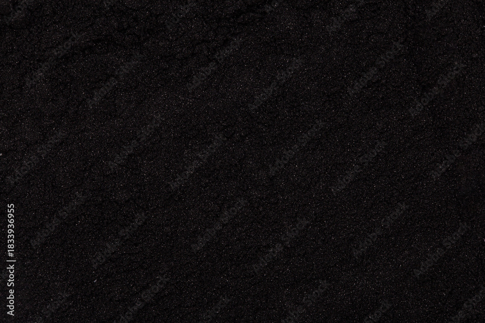 Fototapeta premium Fine black charcoal powder texture captured in close-up detail, showing natural particles and organic surface suitable for cosmetic
