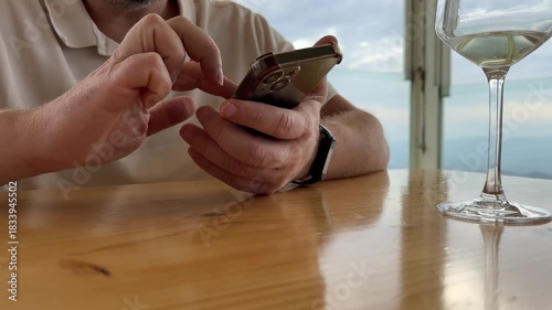 Male hands using mobile phone in cafe. Close up of man browsing smartphone at restaurant in mountains, cropped