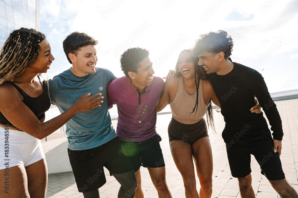 Fototapeta premium A group of five athletes hug and laugh as they walk in a row