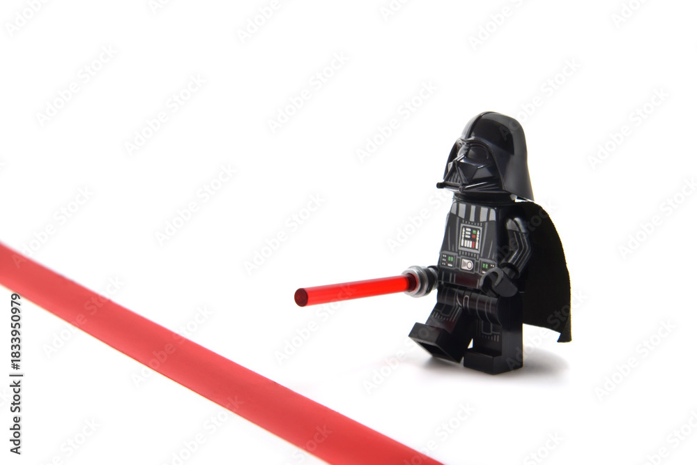 Naklejka premium Lego minifigure of Darth Vader from Star Wars with lightning sword is staying before red line isolated on white. Editorial illustrative image of stop war idea.